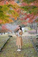 Southeast asian woman enjoys travel concept in autumn park surrounded by colorful leaves and peaceful nature creating serene and beautiful moment of calm and joy photo