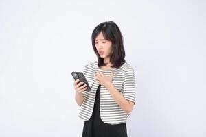 Southeast asian woman in striped jacket holding smartphone with worried expression standing against white background, emotional reaction to message or news photo