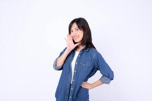 Southeast asian woman in denim jacket smiling and advertising with hand near mouth in cheerful pose on white background photo