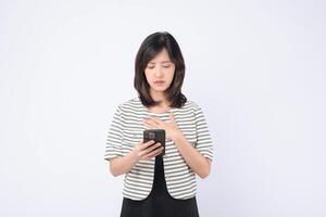 Southeast asian woman uses mobile phone with internet application looking concerned and focused on screen in bright studio setting with white background photo