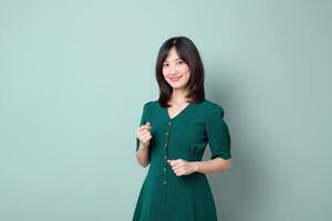 Southeast Asian woman smiling confidently in green dress posing against plain background showing positive emotion and style for online content or shopping inspiration photo