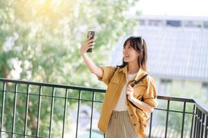 Southeast asian woman enjoys travel concept by taking selfie outdoors with bright natural background and joyful expression on her face photo