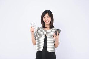 Southeast asian woman happily uses mobile phone application on internet while holding cash in her hand showing excitement and confidence in digital finance photo