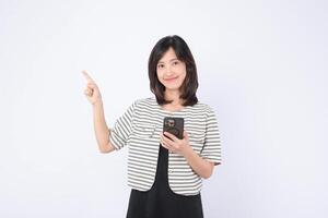 Asian woman holding mobile phone pointing at empty space smiling striped shirt white background cheerful casual copy space photo