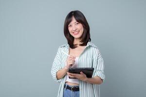 Young Asian woman teacher or student holding digital tablet and pencil, smiling, taking notes, standing over green background photo
