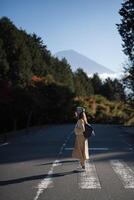 Southeast asian woman stands on quiet road surrounded by forest trees with mountain in background under clear blue sky creating peaceful and calm atmosphere photo