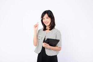 Southeast Asian woman smiling while using internet on digital tablet, holding stylus and standing against white background, expressing confidence and positivity photo