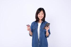 Southeast asian woman smiling while using internet for online shopping holding credit card and smartphone against white background photo