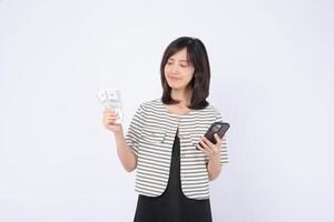 Southeast Asian woman holding cash and using internet on smartphone with happy expression, standing against white background, representing online finance and digital lifestyle photo