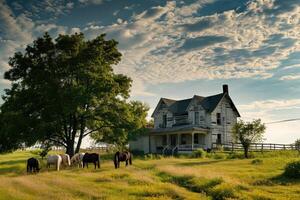 A white farmhouse with a red barn nearby sits in a valley filled with autumn trees and open fields dotted with grazing horses photo