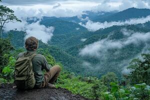 Hiker Overlooking Lush Mountains in Misty Rainforest at Dawn With Dense Greenery and Clouds Surrounding the Landscape photo