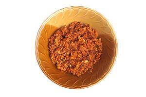 Galangal chili paste in a brown bowl, isolated on white background. Concept, traditional Asian food,rich in flavor, spicy and aromatic, perfect as a dip, condiment, or cooking ingredient in authentic photo