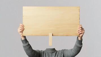 A person holding up a wooden sign with their hands photo