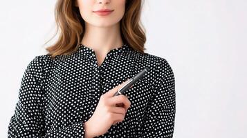 A woman in a polka dot shirt holding a pen photo