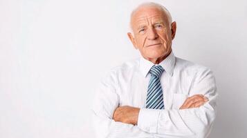 An older man with his arms crossed standing in front of a white background photo