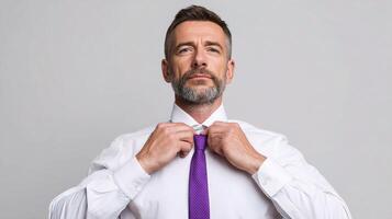 A man with a beard and a white shirt is adjusting his tie photo