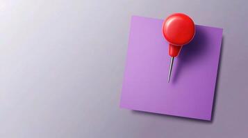 A red pin is stuck to a purple piece of paper photo