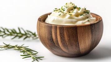 Yogurt in a wooden bowl with rosemary sprig photo
