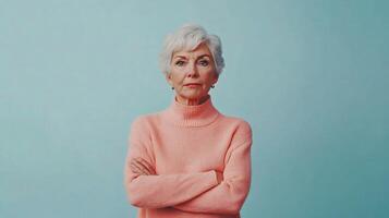 An older woman in a pink sweater standing with her arms crossed photo