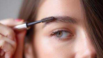 A woman is using a brush to brush her eyebrows photo