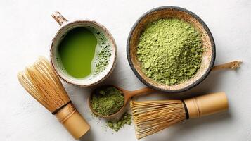 Matcha green tea powder in a bowl and a wooden whisk photo
