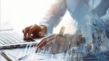 A person is typing on a laptop computer with a city in the background photo