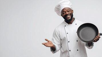 A smiling black man in a chef hat holding a pan photo