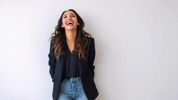 A woman is laughing while standing in front of a white wall photo