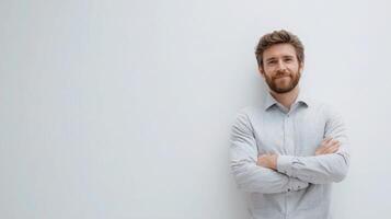 A man with a beard and shirt standing in front of a white wall photo