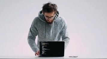 A man in a hoodie is working on a laptop photo