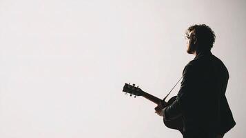 A silhouette of a man playing an acoustic guitar photo