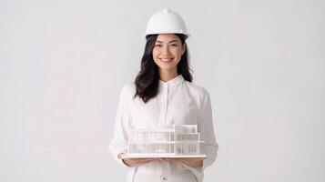 A woman in a hard hat holding a model of a house photo
