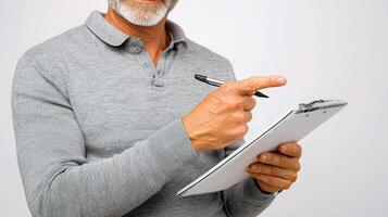 Middle Aged Man Pointing at Notes on Notepad in Gray Sweater photo