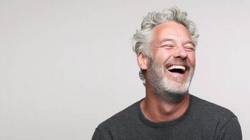 A man with gray hair and a beard laughs photo