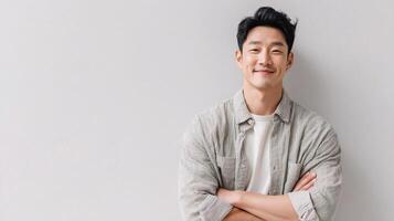 Asian man standing with arms crossed against white wall photo