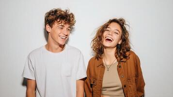 Two young people laughing together in front of a white wall photo