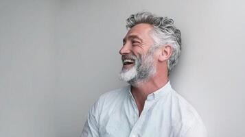A man with a gray beard and white shirt is smiling photo