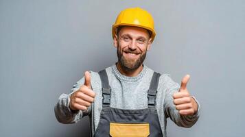 A smiling man in a hard hat and overalls giving the thumbs up photo