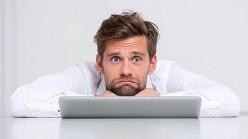 A man is looking at a laptop while sitting on a table photo