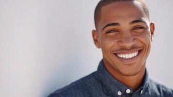 A man smiles while standing in front of a white wall photo