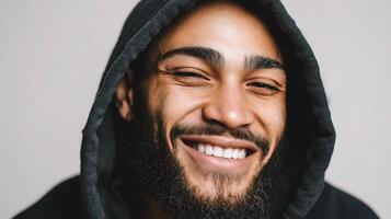 A man with a beard and hoodie smiling photo