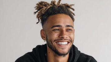 A man with dreadlocks smiles while wearing a black hoodie photo
