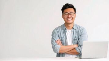 Asian man with laptop standing in front of white table photo