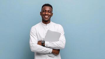 Portrait of a young african man holding a folder and smiling on blue background photo