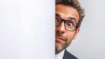 A man in glasses peeking out from behind a wall photo
