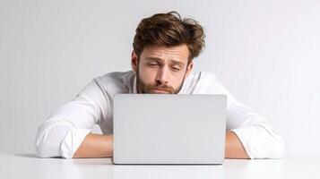 A man is sitting at a table with his head on his laptop photo