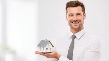A man in a shirt and tie holding a house model photo