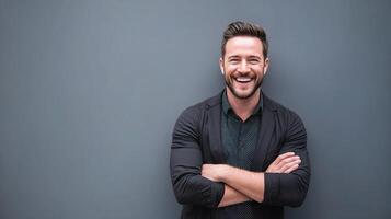 A man with a smile standing in front of a gray wall photo