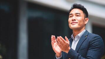 Asian man clapping hands in front of building photo