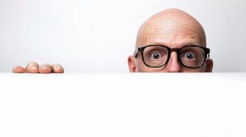 A bald man with glasses peeking over a white board photo